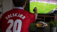 Bilde av en mann i Norge-drakt som ser på VM i fotball